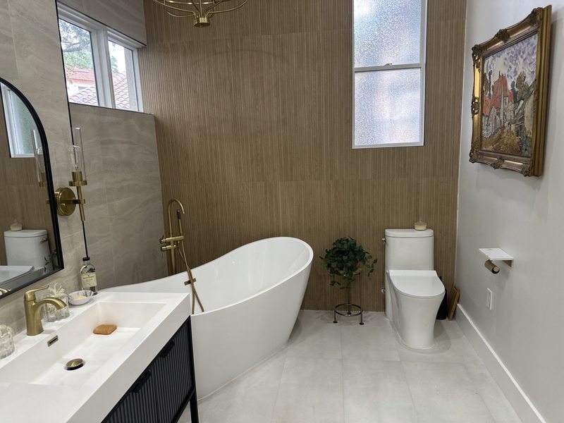 Freestanding bathtub, gold fixtures and a textured accent wall
