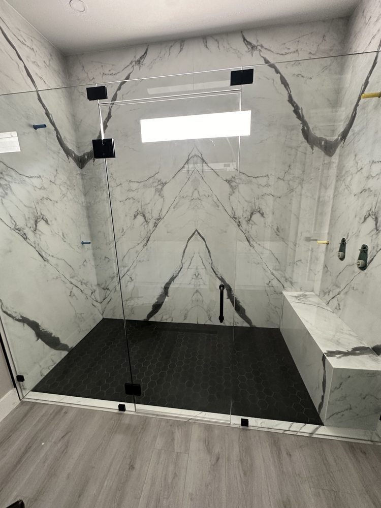 Marble-look wall tile, black fixtures and a glass shower enclosure