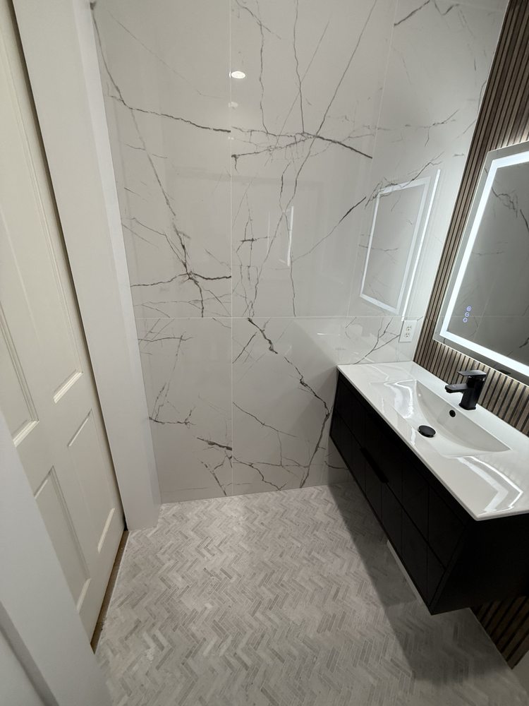 Bathroom with marble-look tile and an illuminated vanity mirror