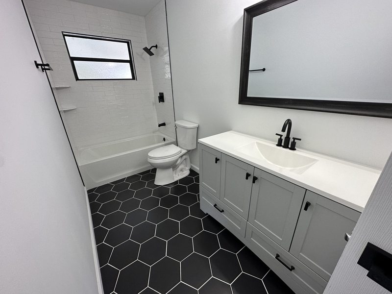 Gray cabinetry, black hexagonal floor tile and a black-framed mirror