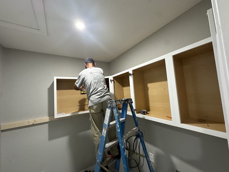 Upper laundry cabinets being installed