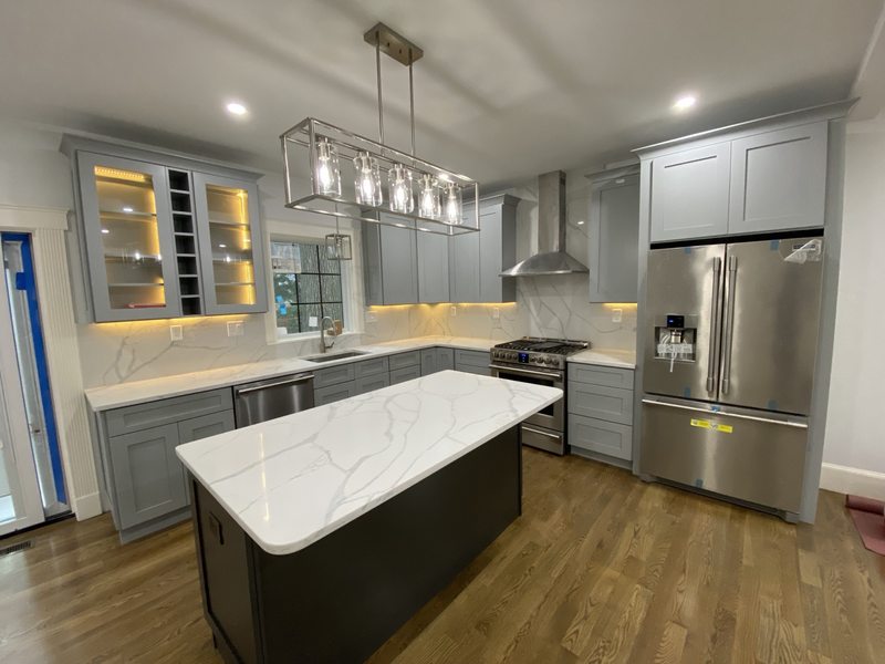Kitchen with gray cabinets, a central island and illuminated glass-front cabinetry