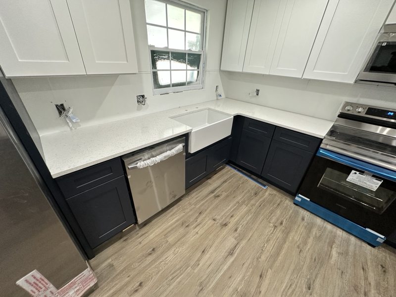 Two-tone kitchen cabinets with a farmhouse sink during installation