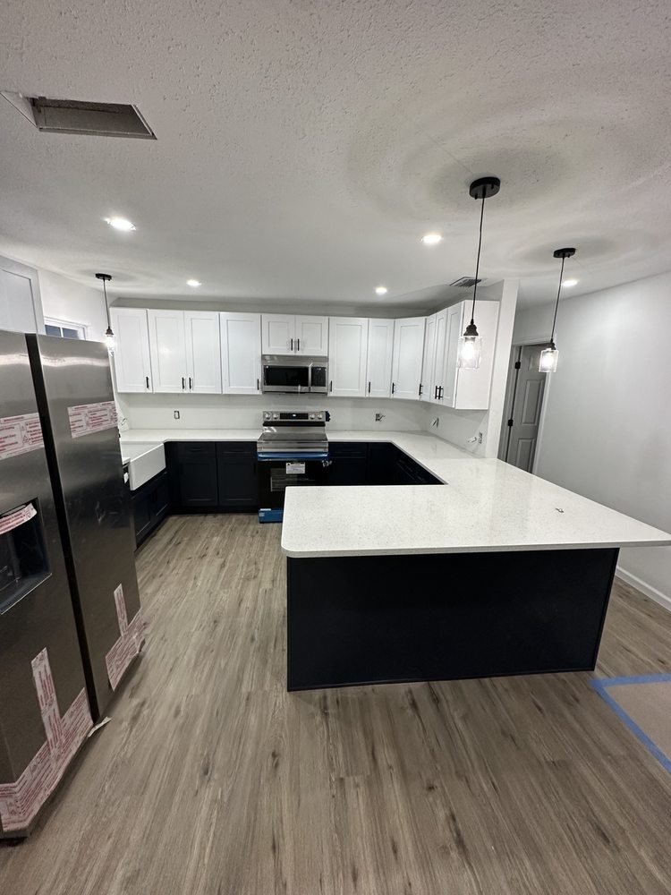 Kitchen installation with white upper cabinets, dark lower cabinets and a white peninsula