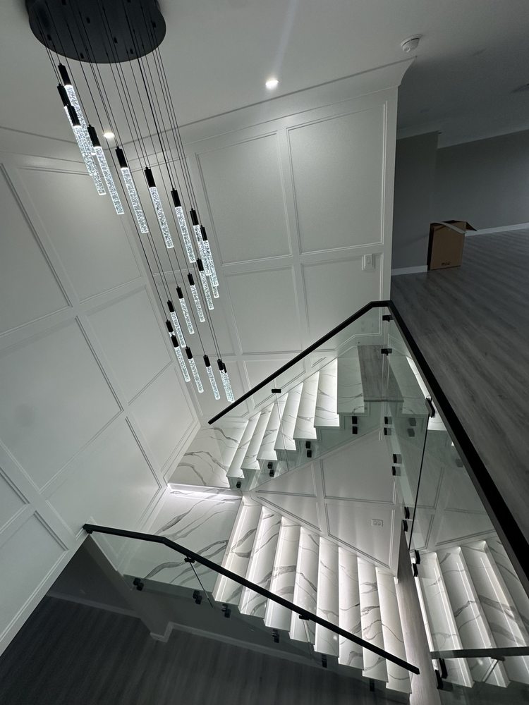 Overhead view of an illuminated marble-look staircase, glass railing and decorative wall molding