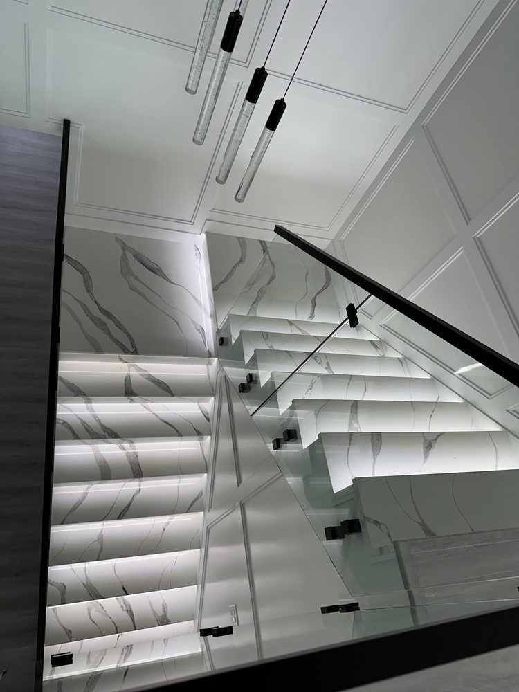 Marble-look staircase finishes with integrated lighting, glass railing and wall molding