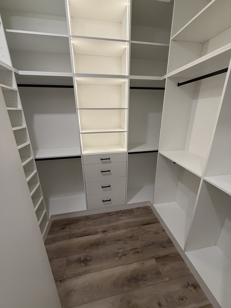 White closet storage with illuminated shelves, hanging space and drawers
