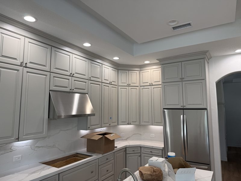 Kitchen cabinet installation with crown molding and marble-look backsplash