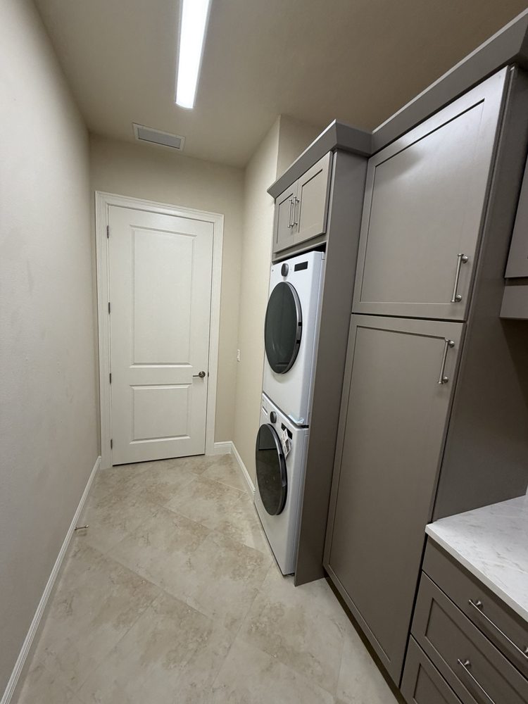 Gray laundry cabinets surrounding stacked appliances