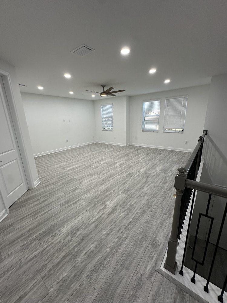 Wood-look flooring in a bright upstairs room with recessed lights and a ceiling fan