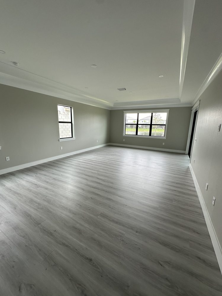 Wood-look flooring in a bright room with large windows and ceiling trim