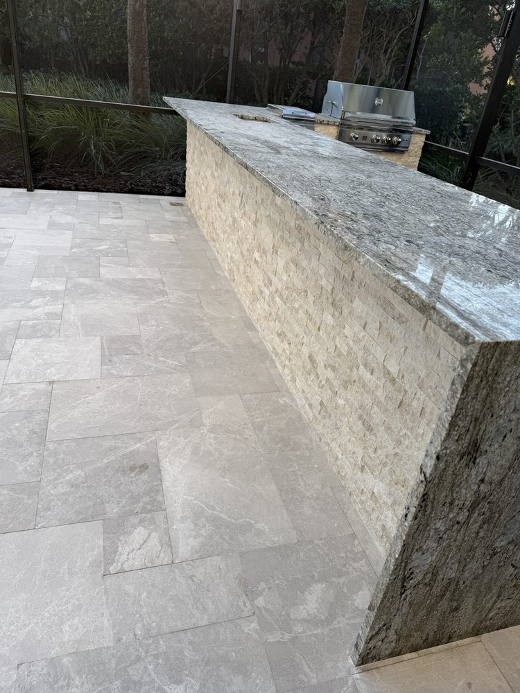 Outdoor kitchen countertop and patio flooring viewed from the seating side