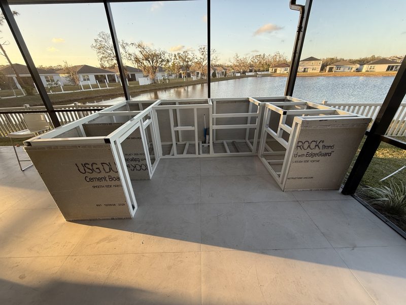 Outdoor kitchen structure under construction on a screened patio