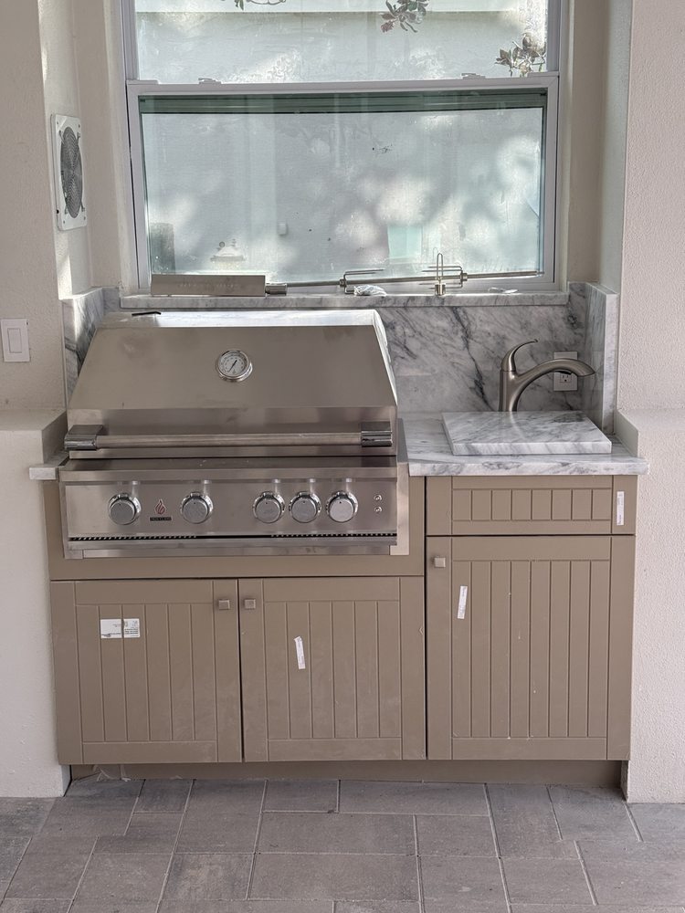 Built-in grill station with cabinet storage, countertop and sink