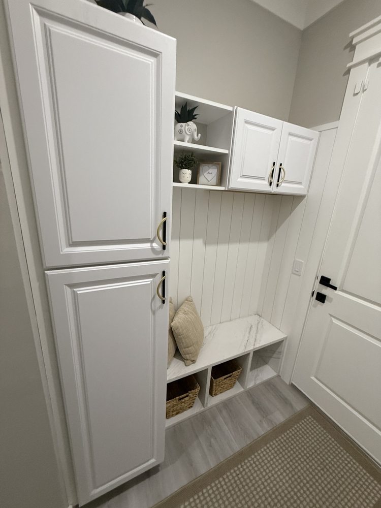 White entryway cabinets with a built-in bench, open storage and hooks