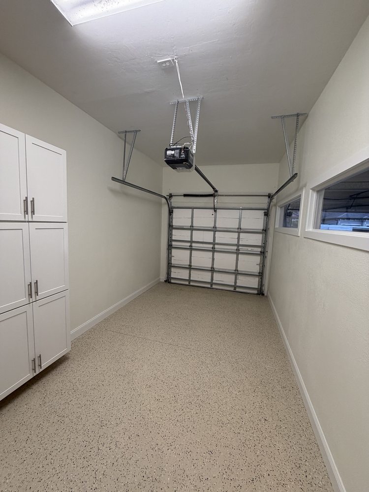 Garage with white storage cabinets, speckled flooring and a high horizontal window