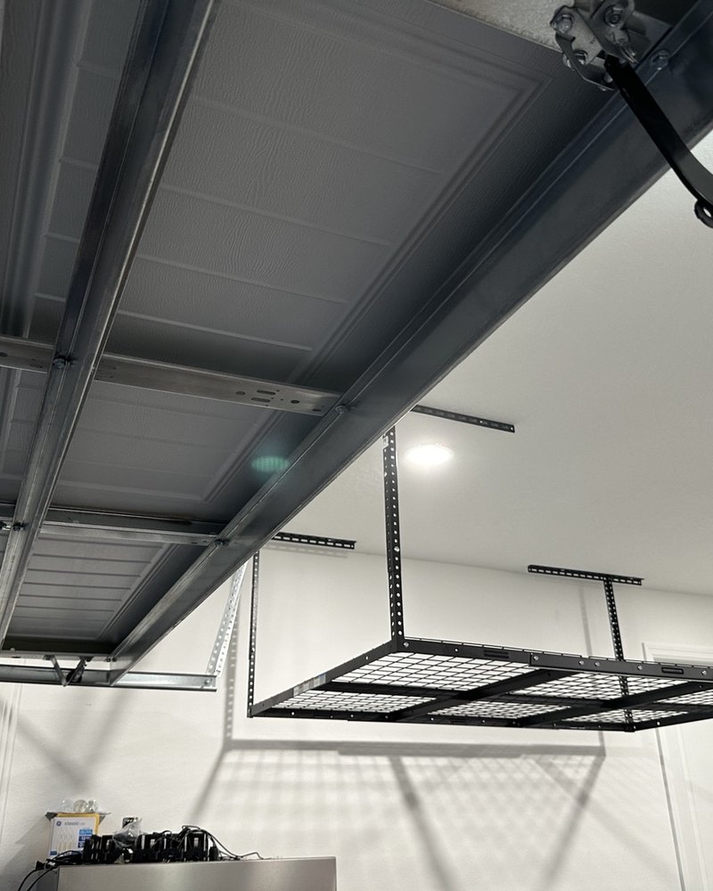 Ceiling-mounted metal storage rack above a garage work area