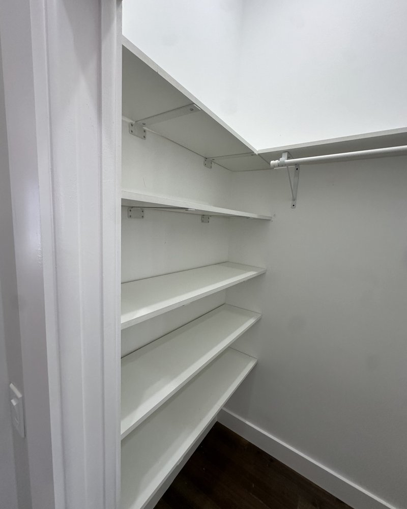 White closet shelves and hanging rail with wood-look flooring