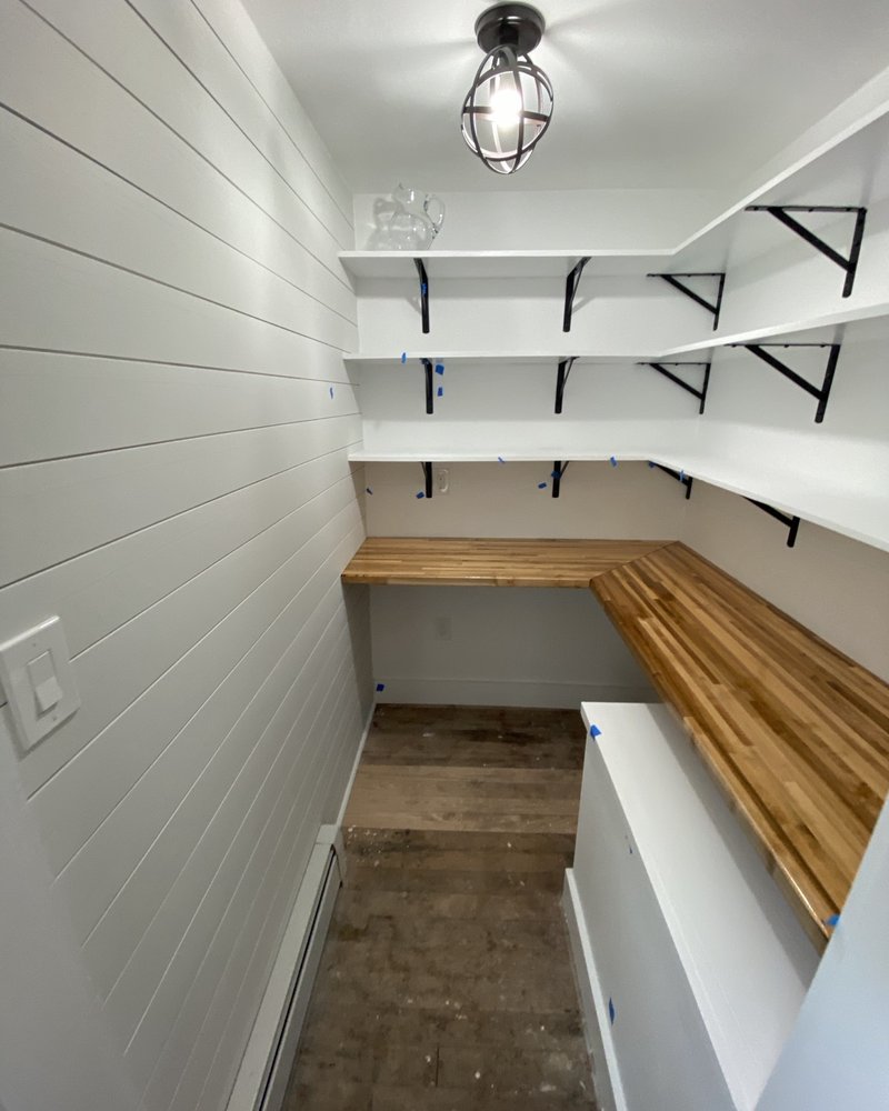 Pantry with open shelves, black brackets, white cabinetry and a wood countertop