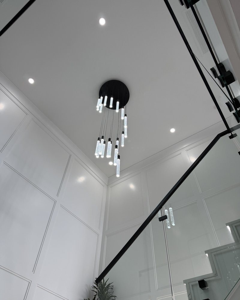 Cascading chandelier above a glass-railed stairwell with decorative wall molding