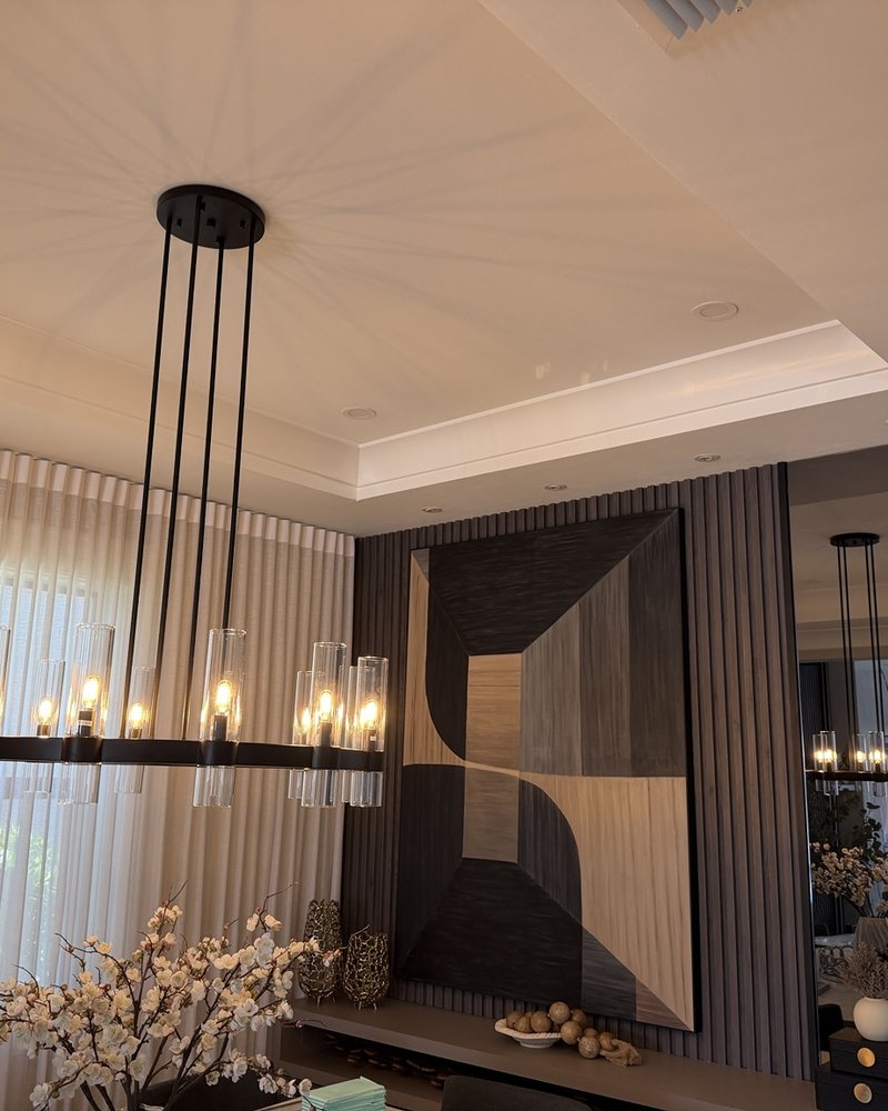 Black dining chandelier beside a wood slat feature wall and mirror