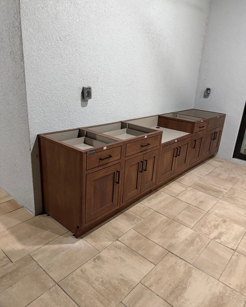 Wood-look outdoor kitchen base cabinets with black handles before countertop installation