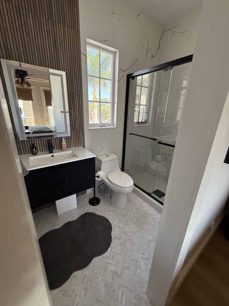 Black vanity, wood-look accent wall and glass shower enclosure