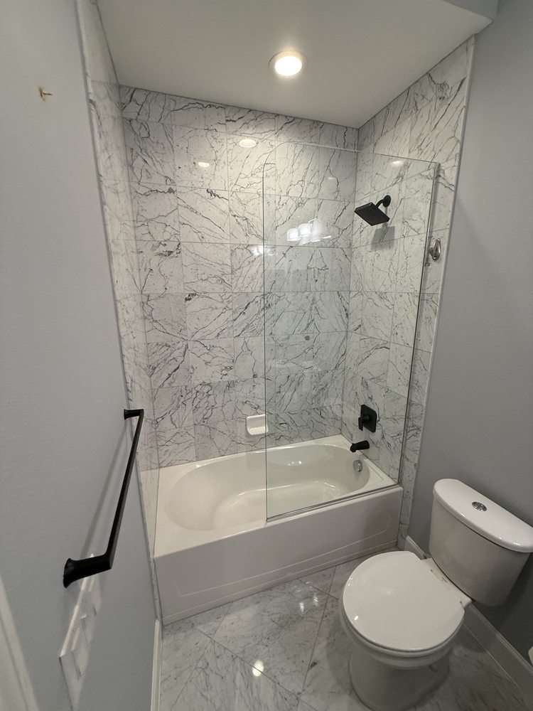 Bathtub surround with marble-look wall tile and black fixtures