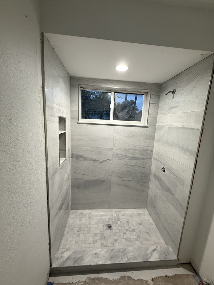 Walk-in shower with light wall tile and a mosaic floor