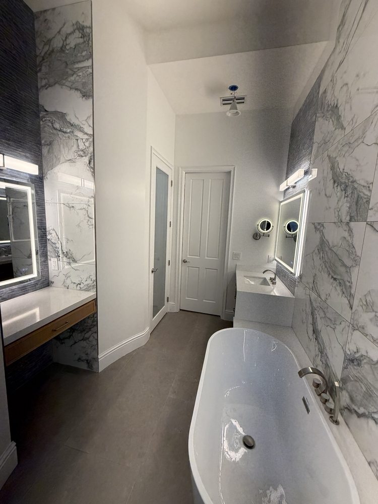 Bathroom project view with a bathtub, dual vanities and illuminated mirrors