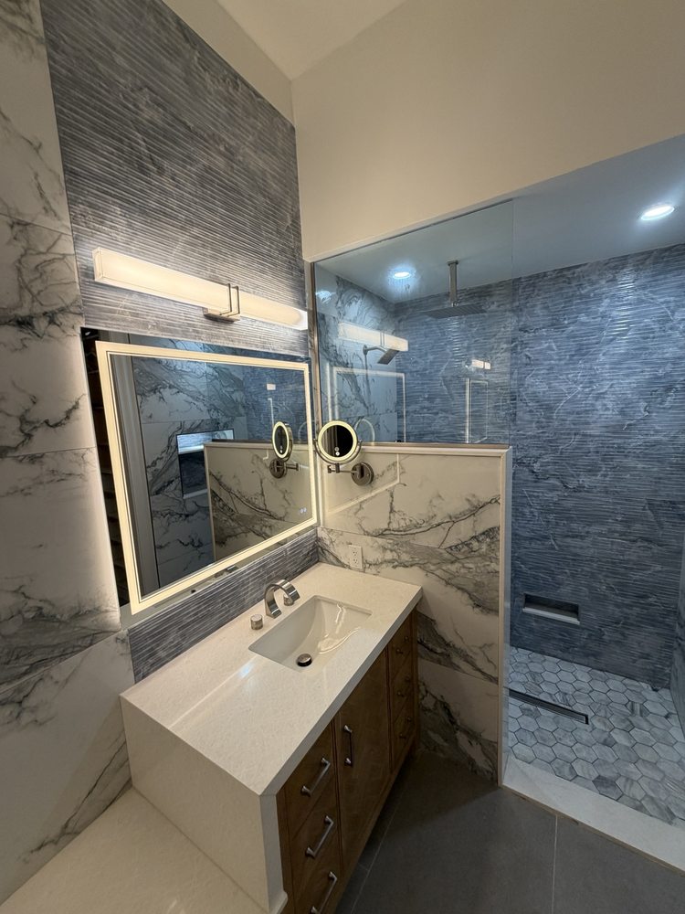 Wood-finish vanity, light countertop and an illuminated mirror