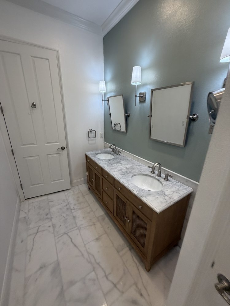 Wood double vanity, two mirrors and a soft green painted accent wall