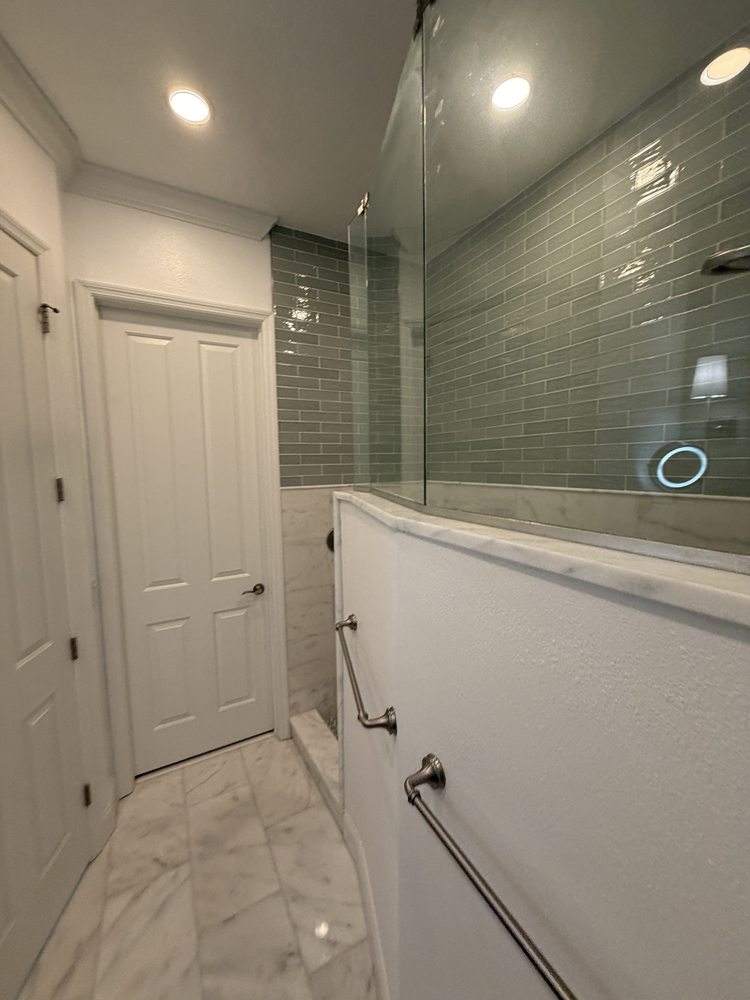 Bathroom shower glass, green tile and marble-look floor