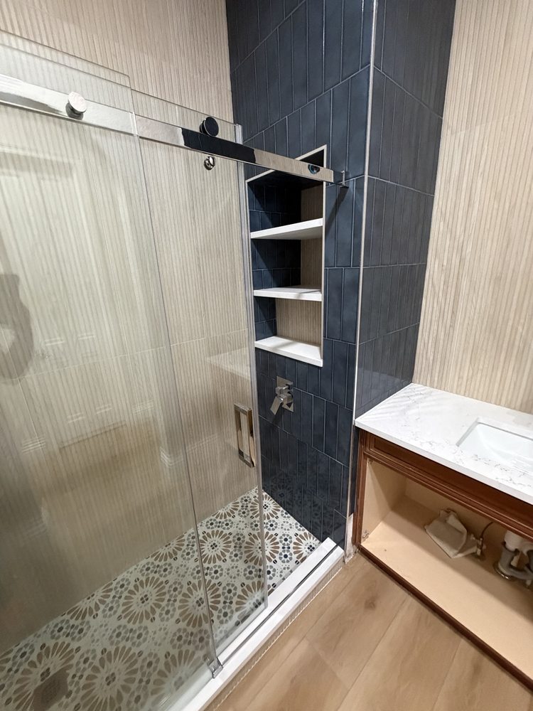 Blue-tiled shower and vanity cabinet during installation