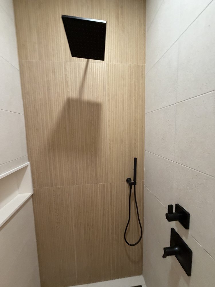Shower with wood-look feature tile, a black rain showerhead and black controls