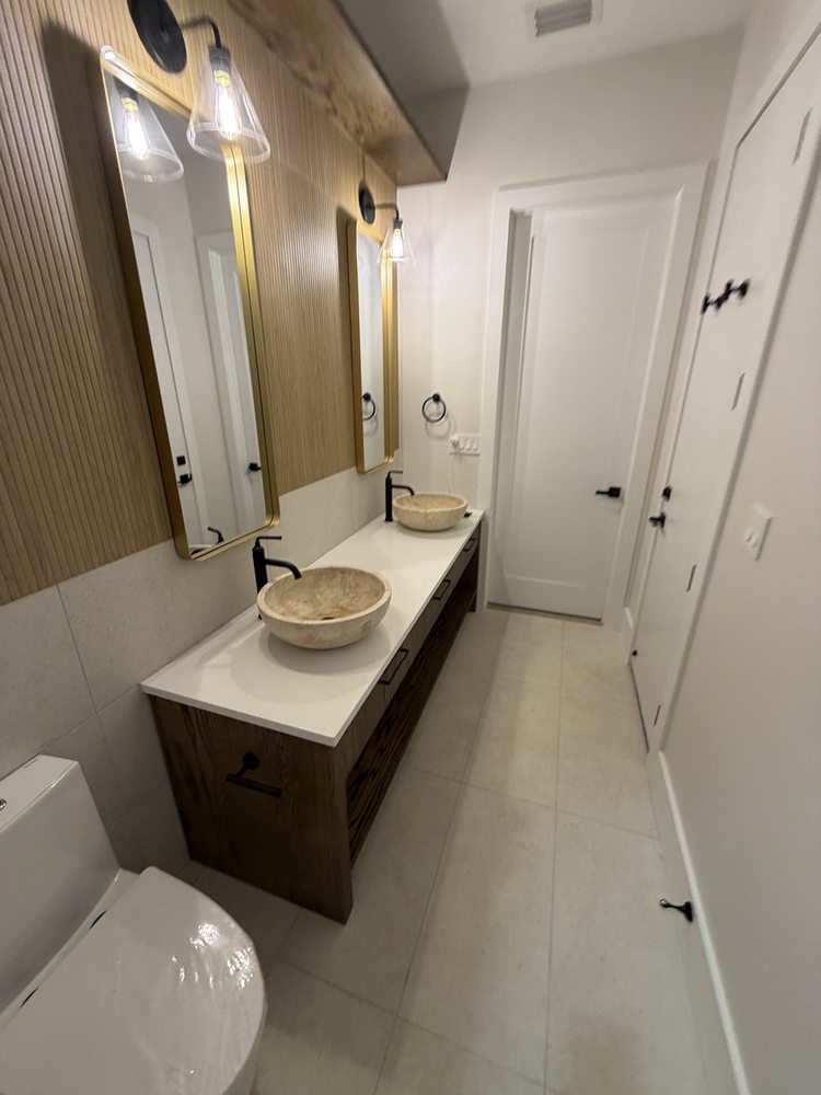 Double vanity with vessel sinks, gold-framed mirrors and wood-look wall finishes