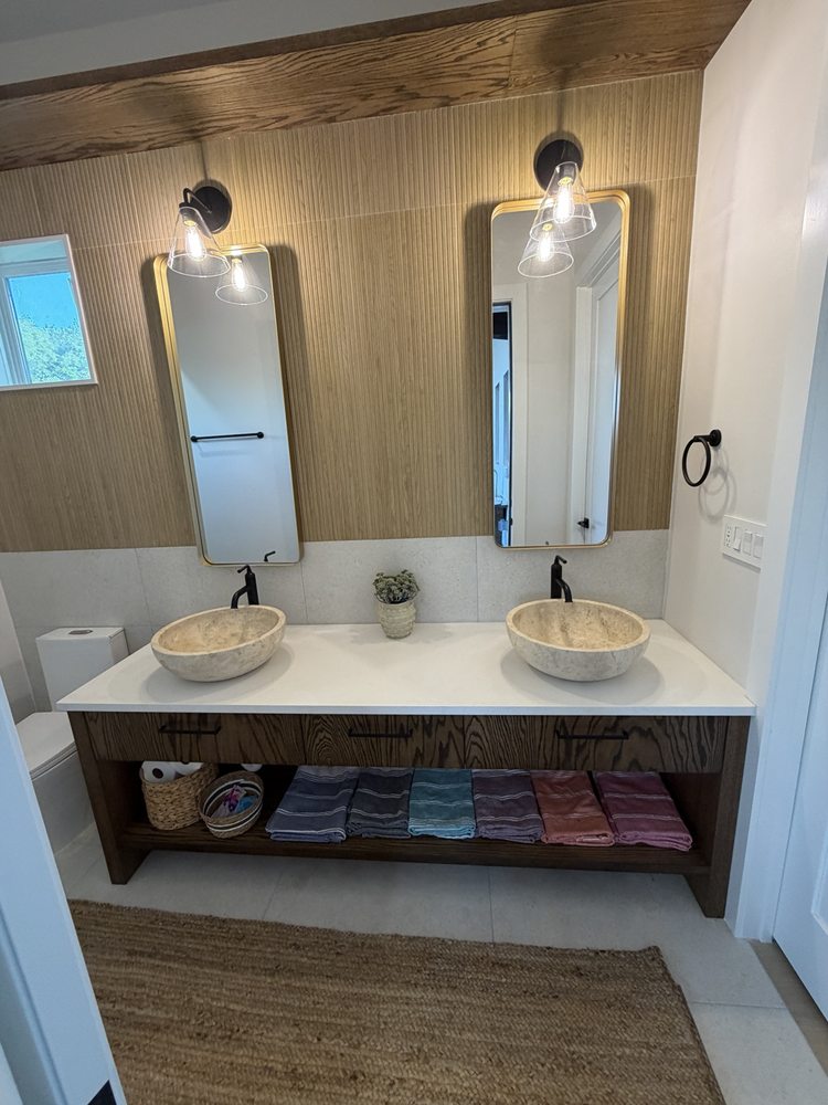 Double vessel sinks, gold-framed mirrors and a wood-look accent wall