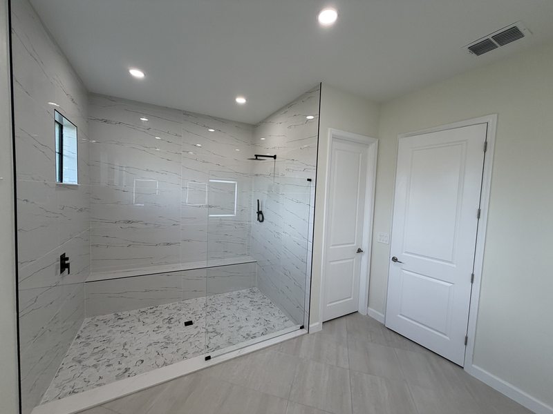 Glass shower enclosure, marble-look tile and a built-in shower bench