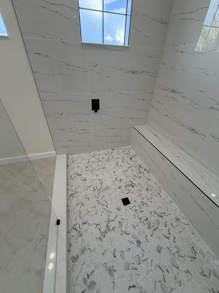 Hexagonal mosaic shower floor beside a marble-look tiled bench