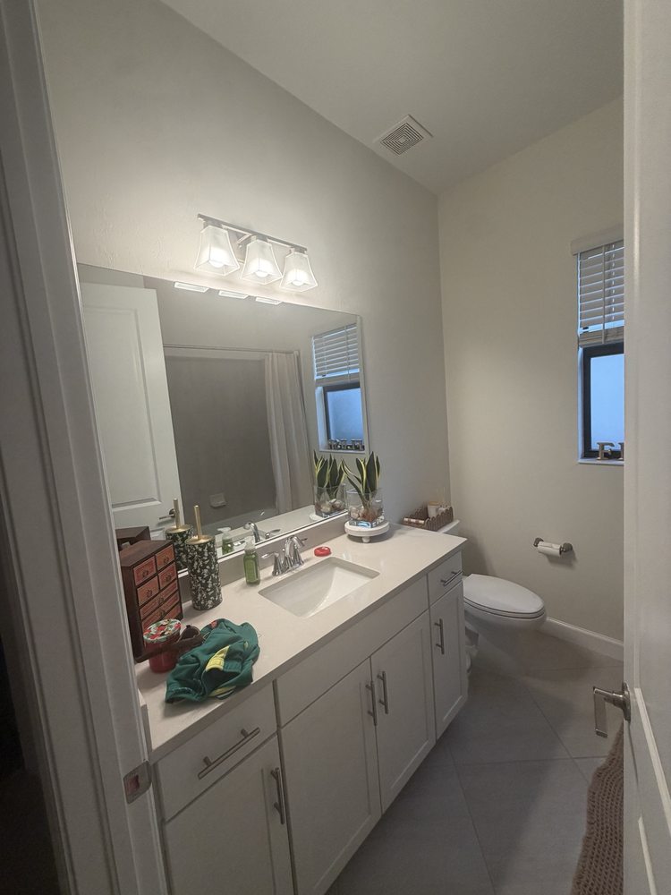 Bathroom vanity with a wide wall mirror and wall lighting