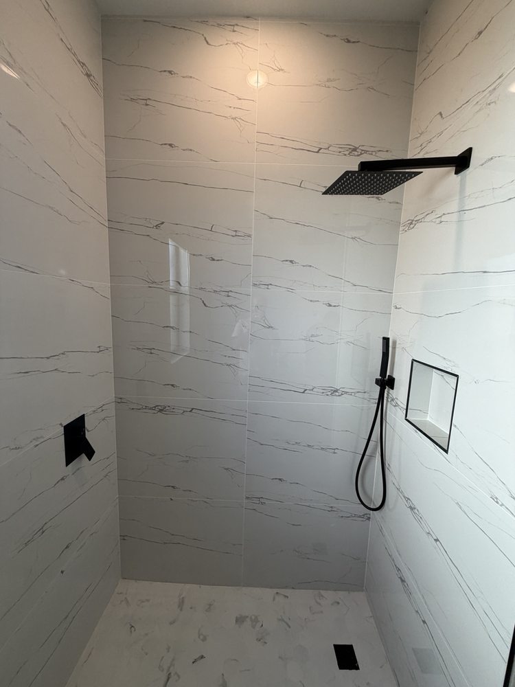 Shower with marble-look wall tile, black fixtures and a recessed niche