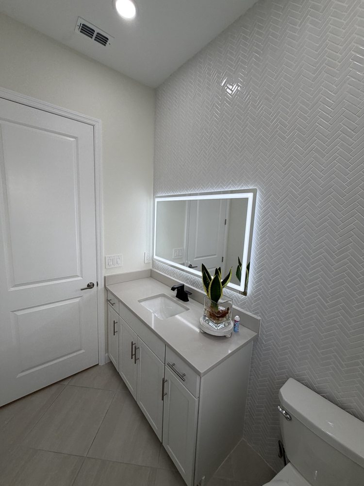 Light vanity with an illuminated mirror against herringbone wall tile