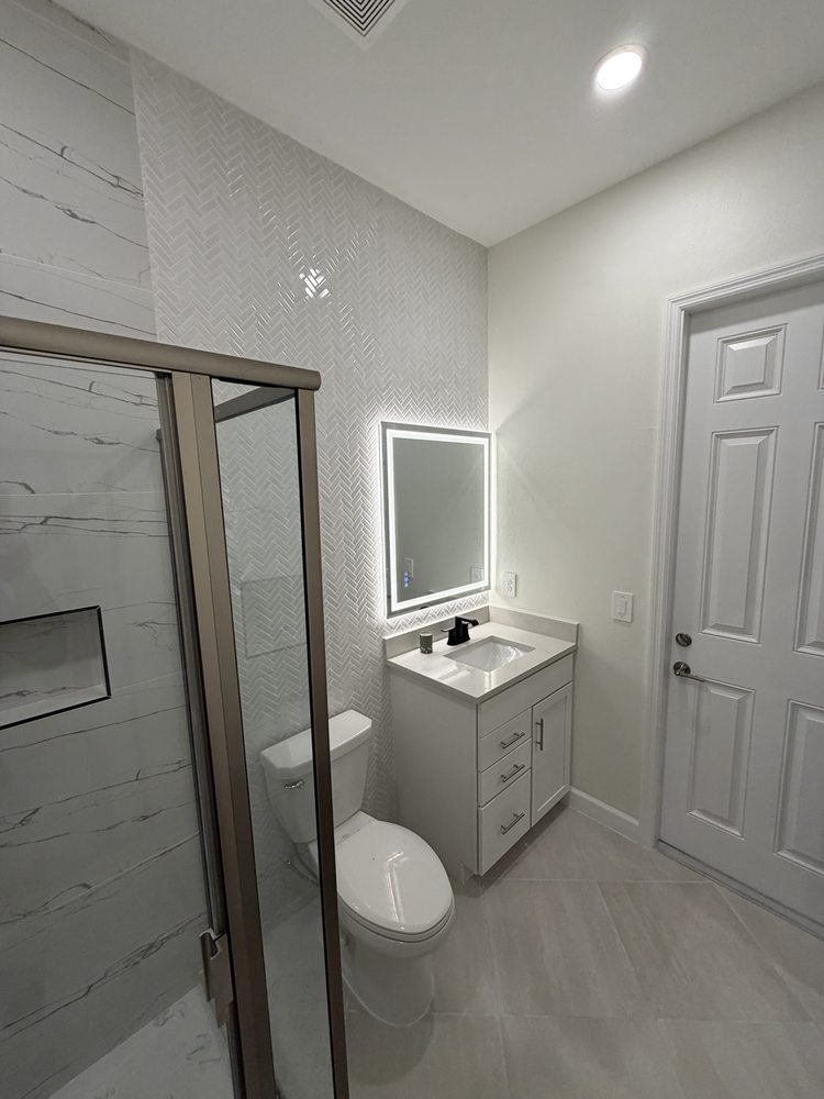 Bathroom with a glass shower enclosure, vanity and illuminated mirror
