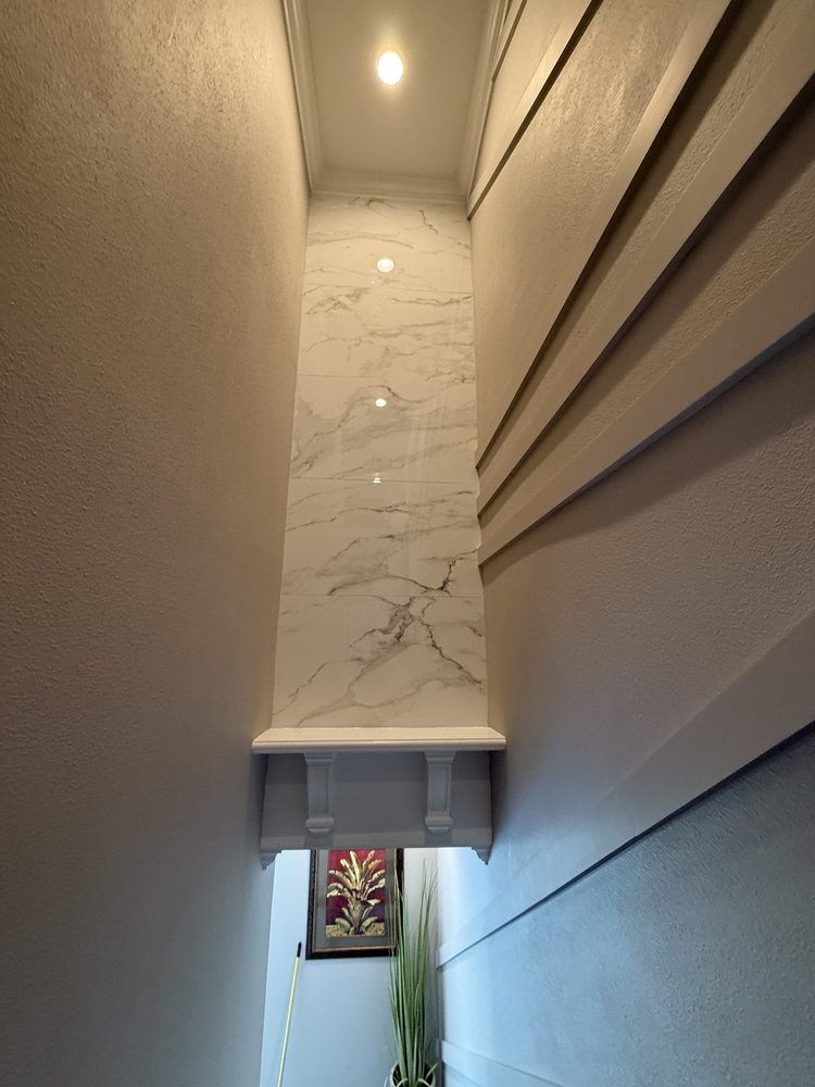 Finished porcelain tile panel with a marble-look finish, decorative shelf and accent lighting