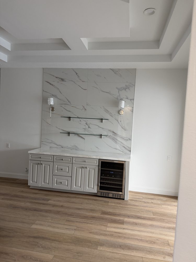 Marble-look porcelain tile feature wall above cabinetry, with glass shelves and wall lights