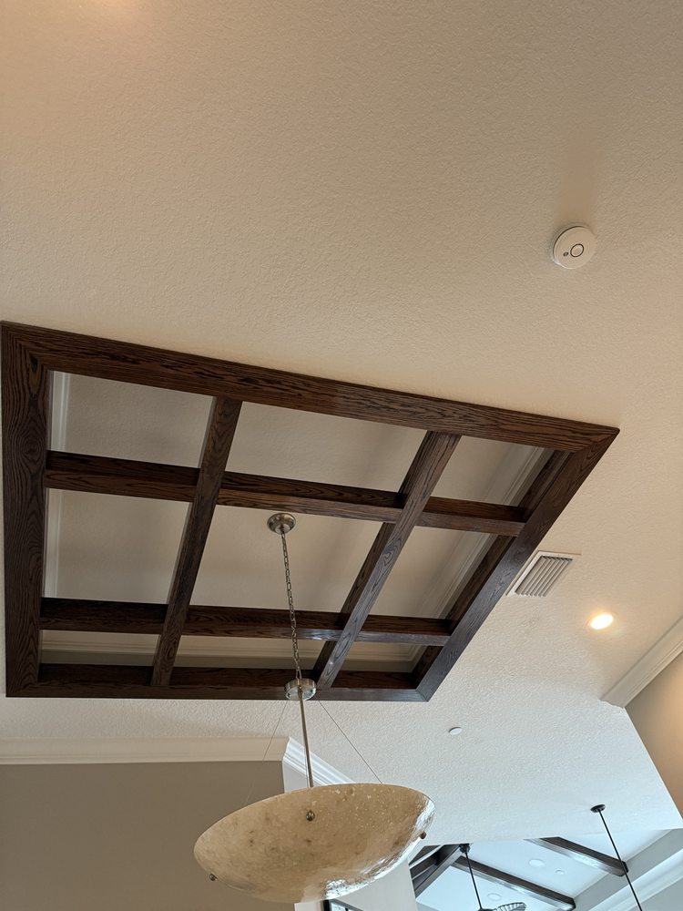 Finished wood beam grid framing a tray ceiling and chandelier