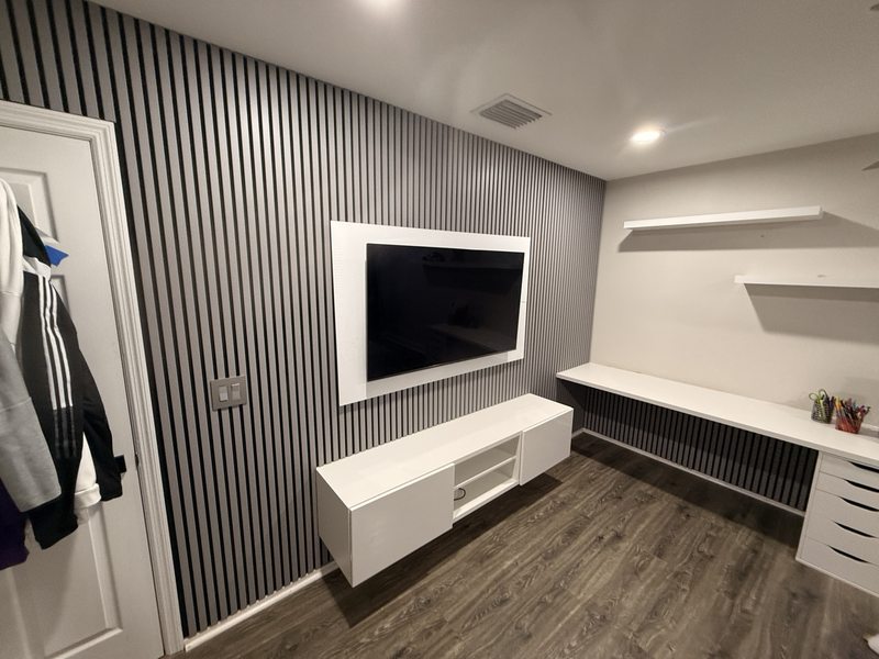 Slatted media wall with white floating cabinetry and adjacent shelving