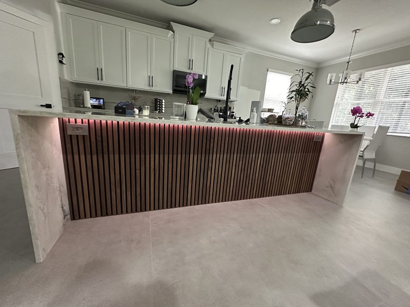 Wood slatted panel on a kitchen island with accent lighting