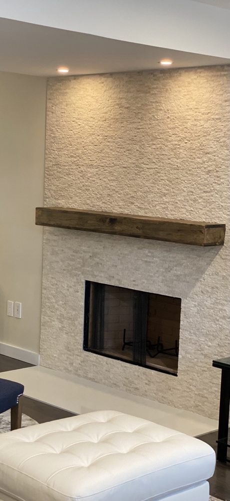Textured fireplace surround with a wood mantel and accent lighting