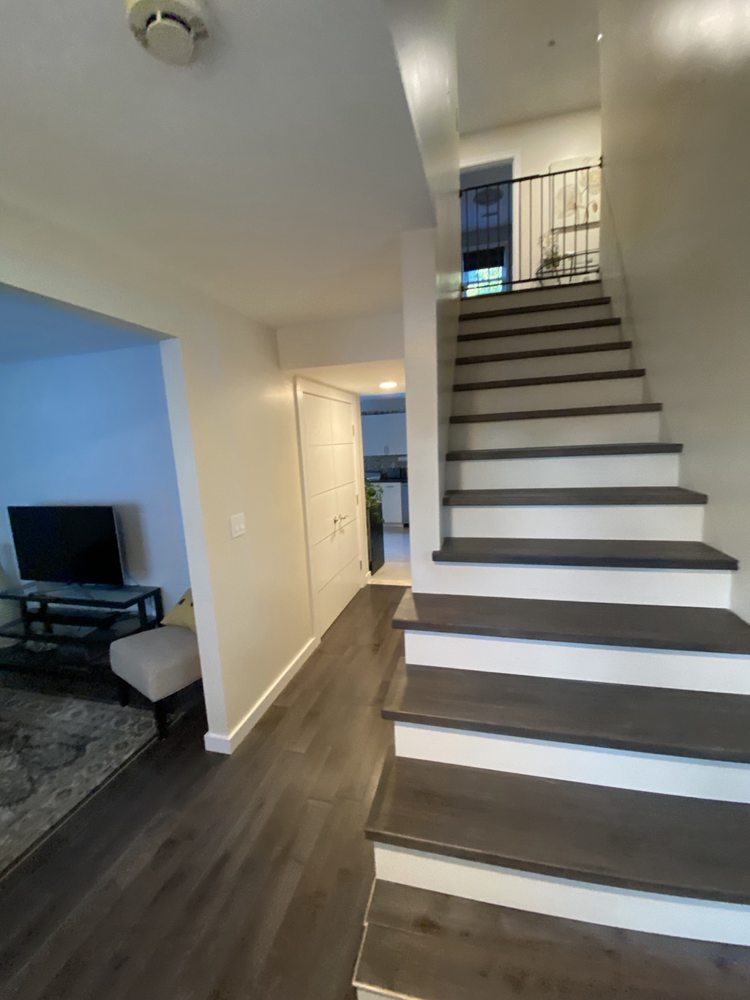 Staircase with dark treads and white risers beside wood-look flooring